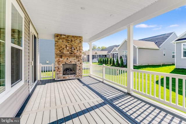 wooden deck with a yard, a residential view, and an outdoor stone fireplace