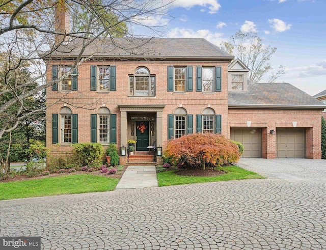 view of front of home featuring brick siding, a chimney, and a garage