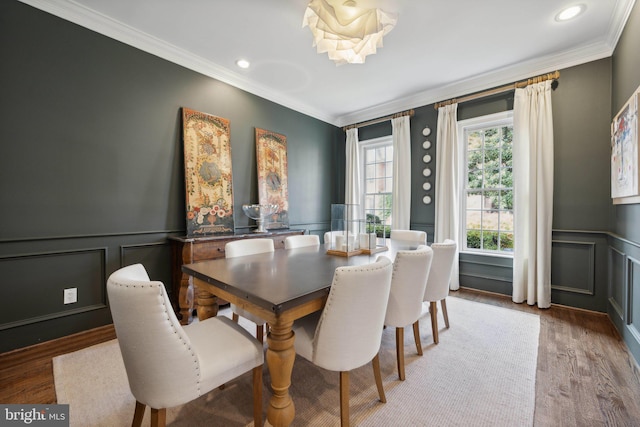 dining space featuring wood finished floors, wainscoting, and ornamental molding