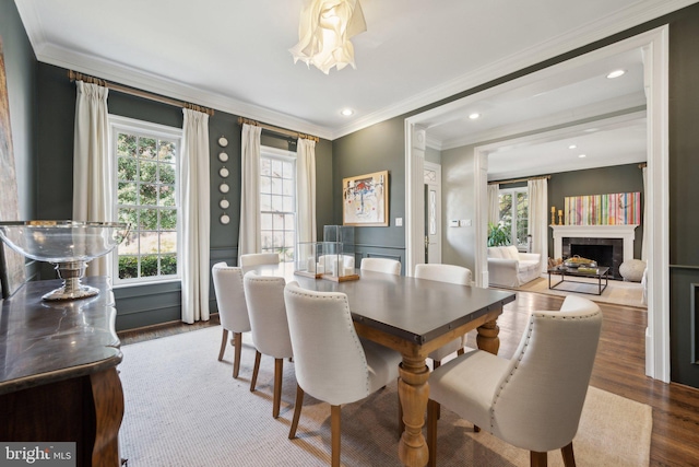 dining room with a fireplace, recessed lighting, wood finished floors, and ornamental molding