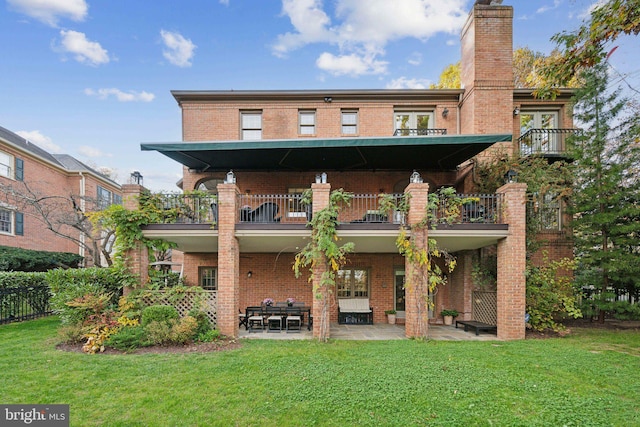 back of house with a patio, a lawn, and brick siding