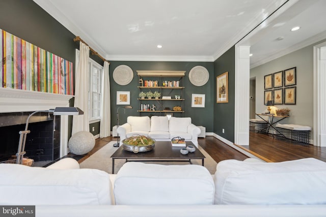 living area with baseboards, ornamental molding, recessed lighting, a fireplace, and wood finished floors