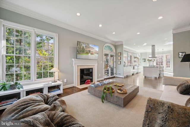 living room with wood finished floors, baseboards, a fireplace with flush hearth, recessed lighting, and crown molding