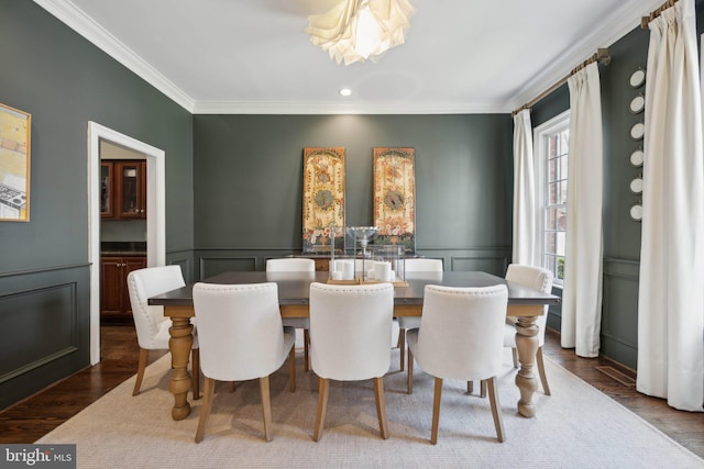 dining room featuring a wainscoted wall, a decorative wall, dark wood finished floors, and ornamental molding