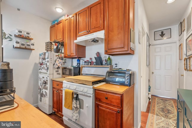 kitchen with under cabinet range hood, a toaster, butcher block counters, wood finished floors, and white appliances