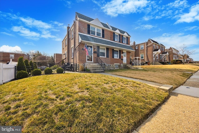 view of front of house with brick siding, a front lawn, fence, a residential view, and a chimney