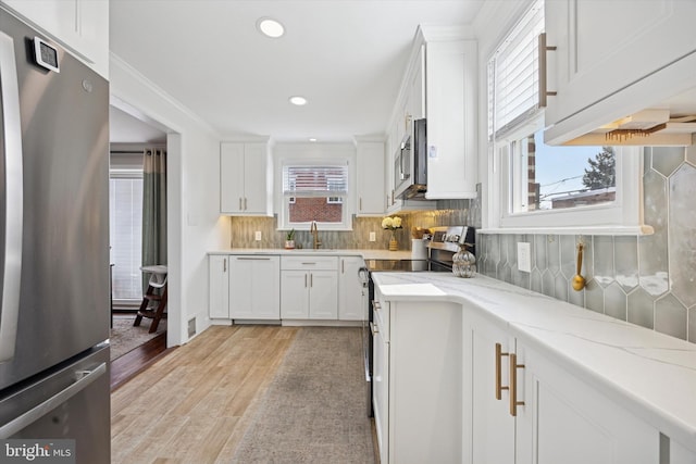 kitchen with a sink, stainless steel appliances, tasteful backsplash, and white cabinets