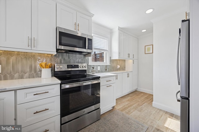 kitchen with light wood-style flooring, backsplash, white cabinetry, stainless steel appliances, and baseboards