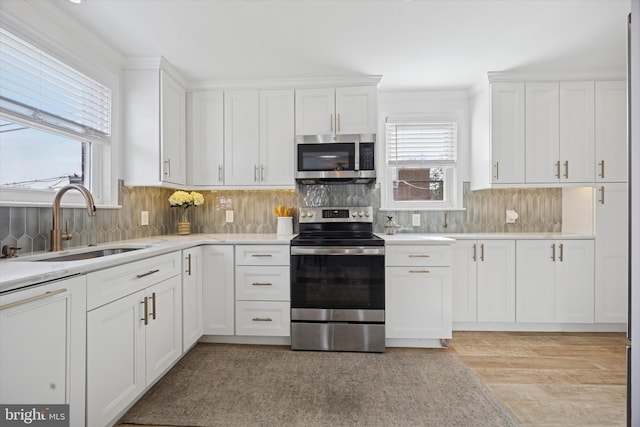 kitchen featuring a sink, light countertops, white cabinets, appliances with stainless steel finishes, and tasteful backsplash