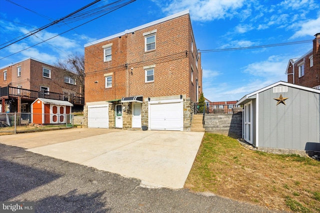 exterior space featuring fence, driveway, a shed, an outdoor structure, and brick siding