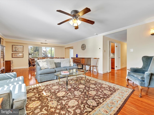 living room featuring ceiling fan, baseboards, wood finished floors, and ornamental molding