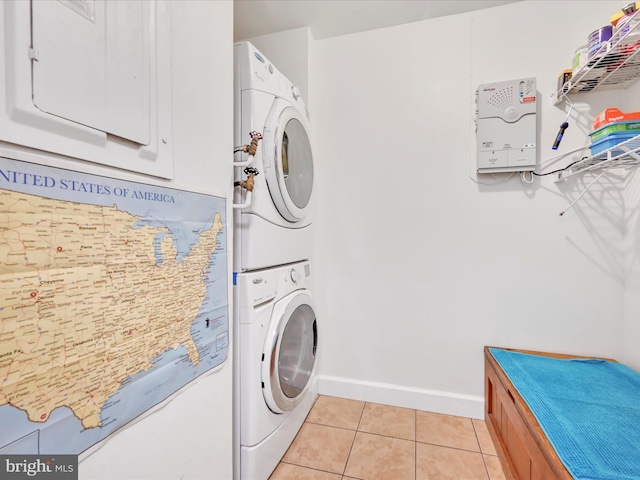 laundry room with baseboards, stacked washer and dryer, light tile patterned flooring, and laundry area