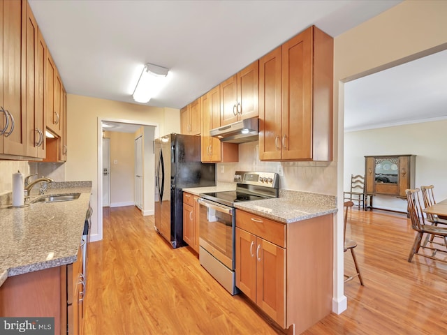 kitchen with under cabinet range hood, a sink, tasteful backsplash, freestanding refrigerator, and stainless steel electric range