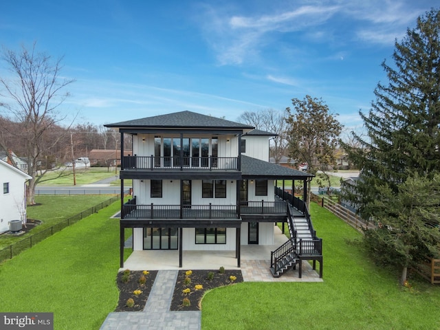 back of property with a patio, a lawn, board and batten siding, and a shingled roof