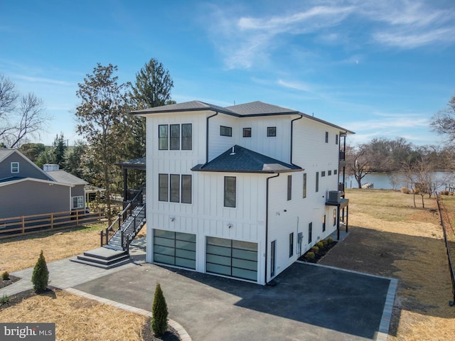 view of front of property featuring aphalt driveway, fence, stairway, board and batten siding, and a shingled roof