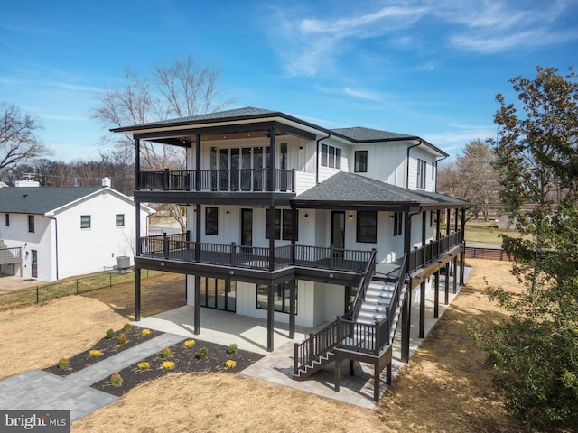 view of front of home with fence, a patio area, board and batten siding, and roof with shingles