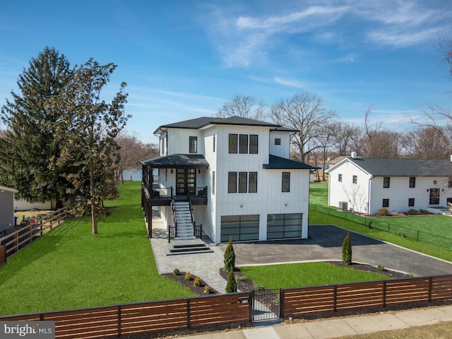 view of front of house featuring driveway, a fenced front yard, stairway, board and batten siding, and a front yard