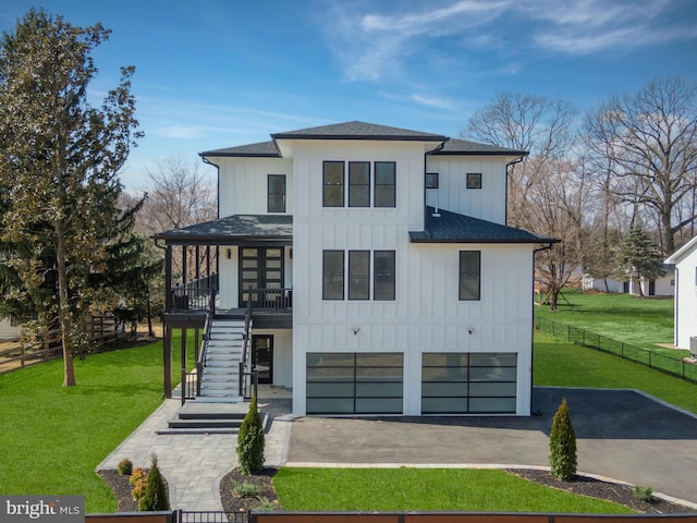 view of front of property featuring aphalt driveway, stairway, board and batten siding, and a front lawn