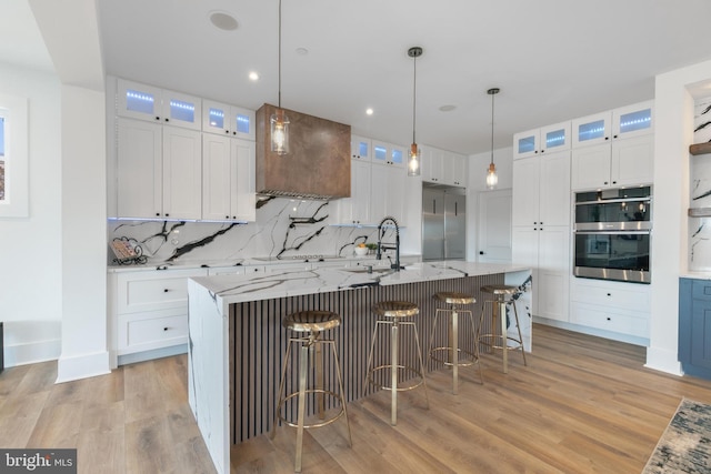 kitchen with white cabinetry, decorative backsplash, light wood finished floors, and stainless steel appliances