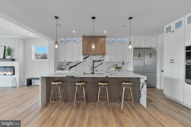 kitchen featuring backsplash, light wood-style floors, a large island, and appliances with stainless steel finishes