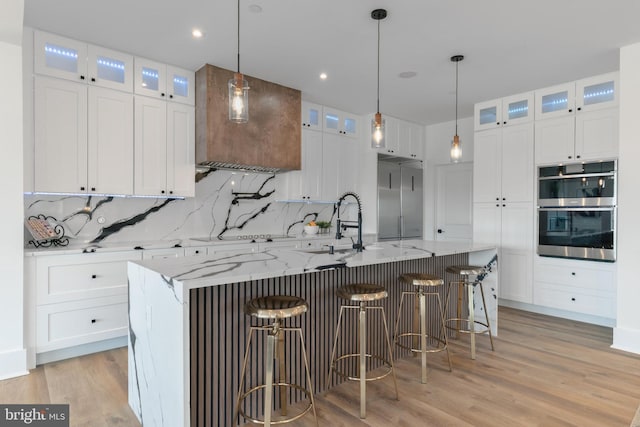 kitchen with backsplash, light wood-style flooring, appliances with stainless steel finishes, and white cabinets