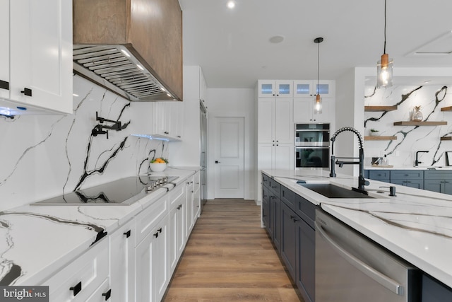 kitchen featuring ventilation hood, wood finished floors, stainless steel appliances, a sink, and white cabinets