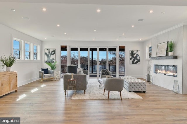 living area featuring baseboards, recessed lighting, a fireplace, crown molding, and light wood-type flooring