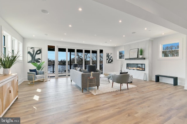 living room with recessed lighting, baseboards, a glass covered fireplace, and light wood finished floors