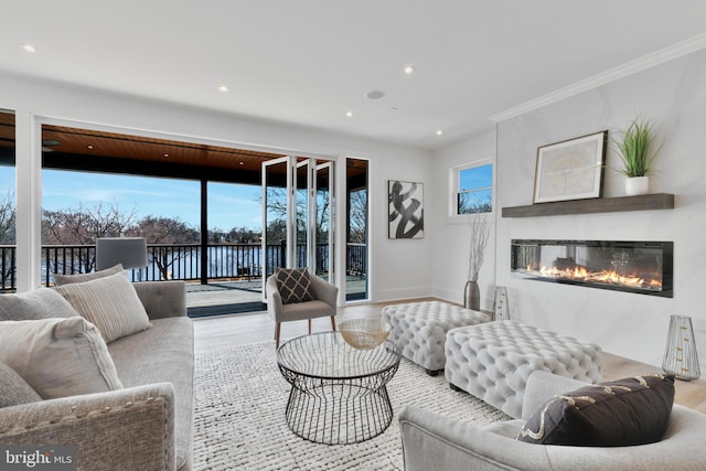 living room with a glass covered fireplace, crown molding, recessed lighting, and wood finished floors