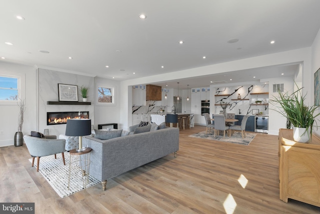 living room with wine cooler, recessed lighting, light wood-type flooring, and a large fireplace