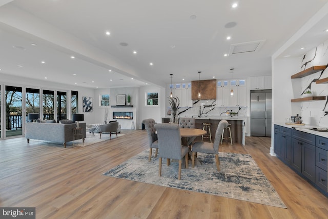 dining area featuring light wood-type flooring, a premium fireplace, and recessed lighting