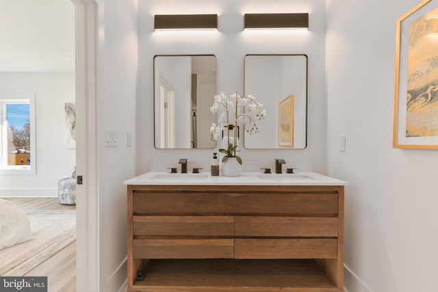 bathroom featuring double vanity, baseboards, and a sink