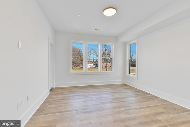 unfurnished room with plenty of natural light, visible vents, baseboards, and light wood-style floors