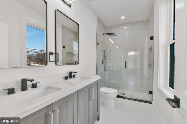 bathroom with double vanity, a stall shower, toilet, and a sink