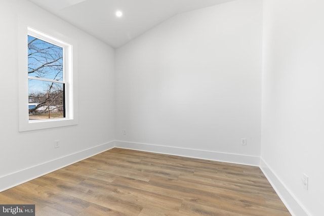 spare room featuring vaulted ceiling, recessed lighting, baseboards, and wood finished floors