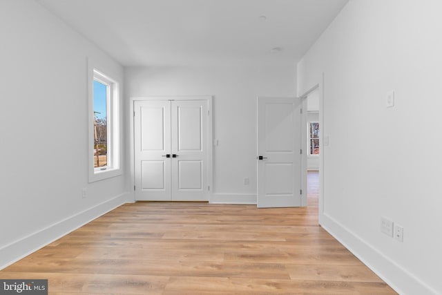 unfurnished bedroom featuring a closet, baseboards, and light wood-style floors