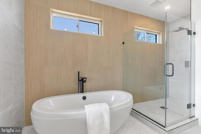 full bathroom with visible vents, a freestanding bath, tile walls, and a shower stall