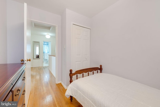 bedroom featuring attic access, baseboards, light wood-type flooring, and a closet