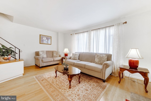 living area with stairway, baseboards, and wood finished floors