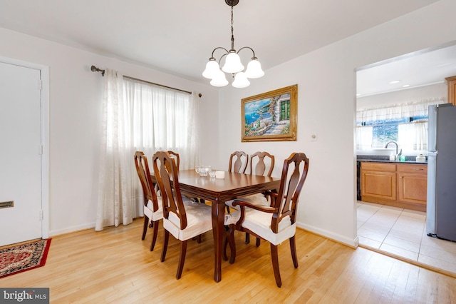 dining room featuring baseboards, light wood-style floors, and a chandelier