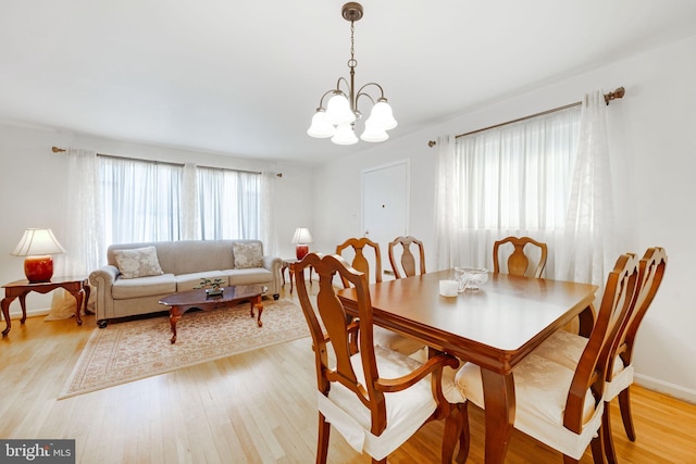 dining area with baseboards, a notable chandelier, and light wood finished floors