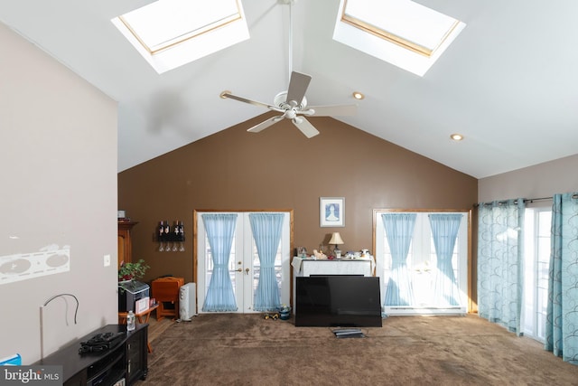 living room with a ceiling fan, a skylight, carpet, and high vaulted ceiling