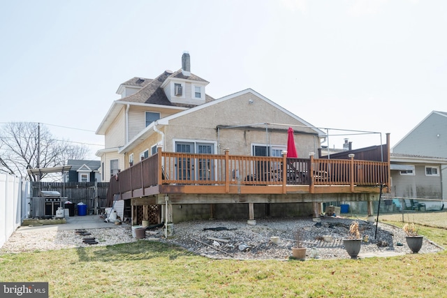 rear view of property with a patio area, a lawn, a deck, and fence