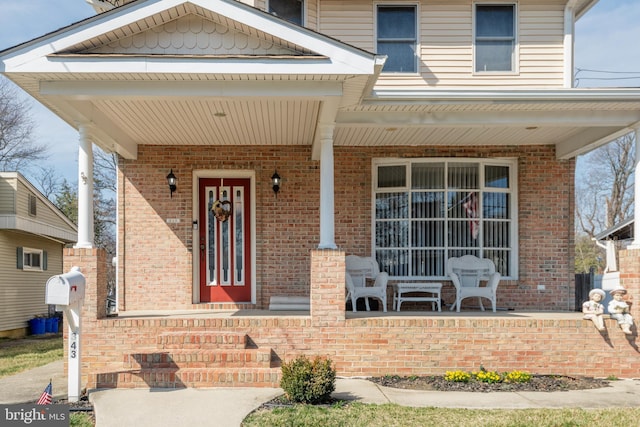 entrance to property featuring brick siding and covered porch