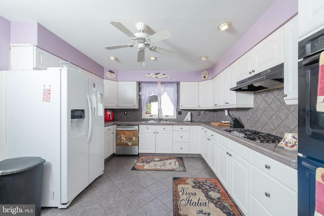 kitchen featuring under cabinet range hood, a sink, backsplash, stainless steel appliances, and white cabinets