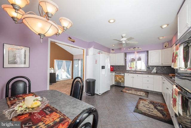 kitchen with dark tile patterned flooring, backsplash, white cabinetry, white fridge with ice dispenser, and dishwasher