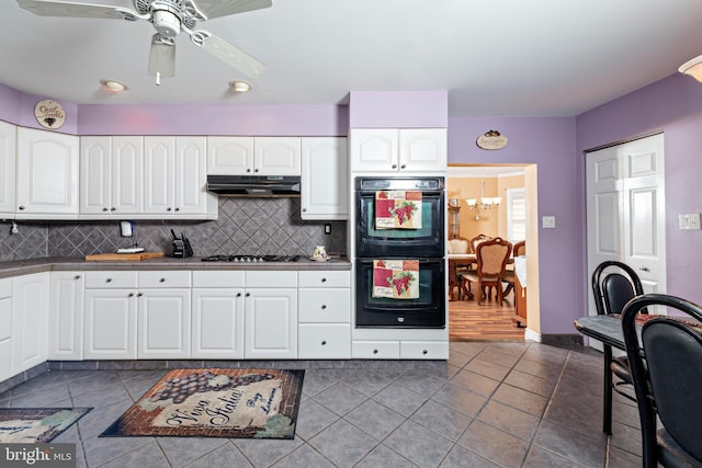 kitchen with under cabinet range hood, dark tile patterned floors, white cabinets, gas cooktop, and dobule oven black