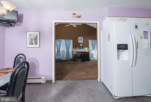 kitchen with tile patterned flooring, carpet floors, baseboard heating, white refrigerator with ice dispenser, and white cabinets