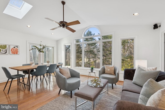 living area featuring baseboards, recessed lighting, ceiling fan, light wood-style floors, and lofted ceiling with skylight