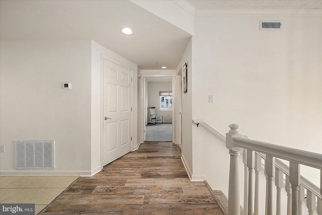 hall with wood finished floors, crown molding, an upstairs landing, and visible vents